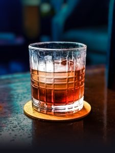 A rich and smooth Secret Handshake cocktail served in a textured glass over a large ice cube at Lefty’s in Magnolia, Arkansas, capturing the essence of a classic Old Fashioned.